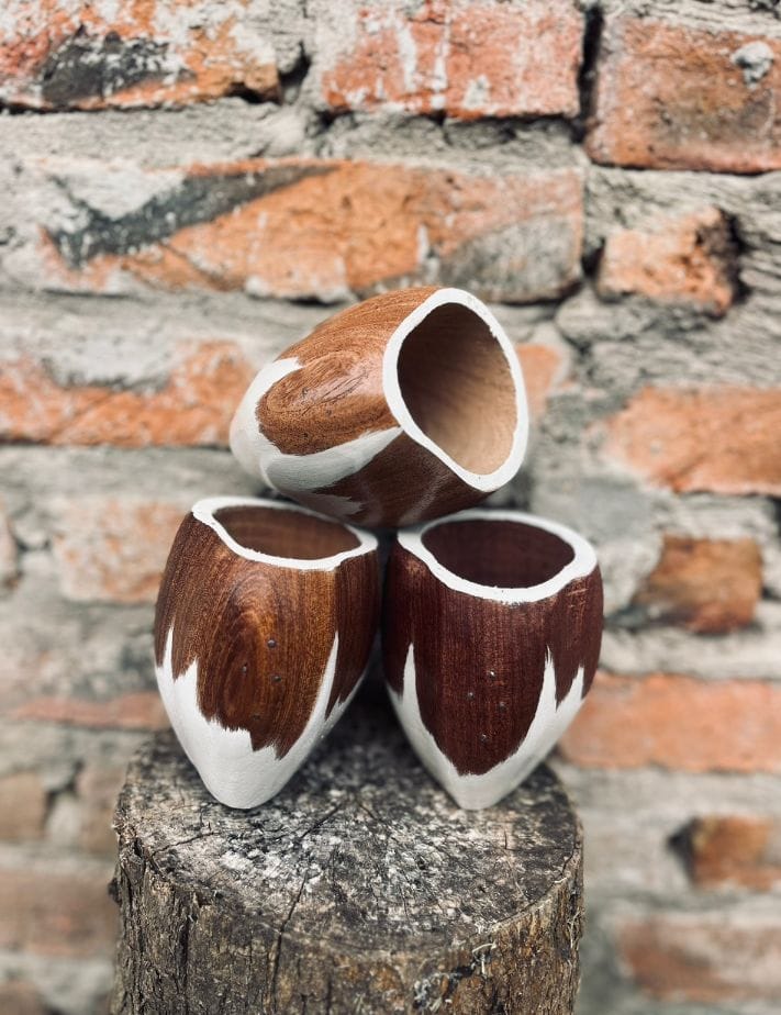 Tres mates de madera pintados de blanco y marrón sobre un tronco
