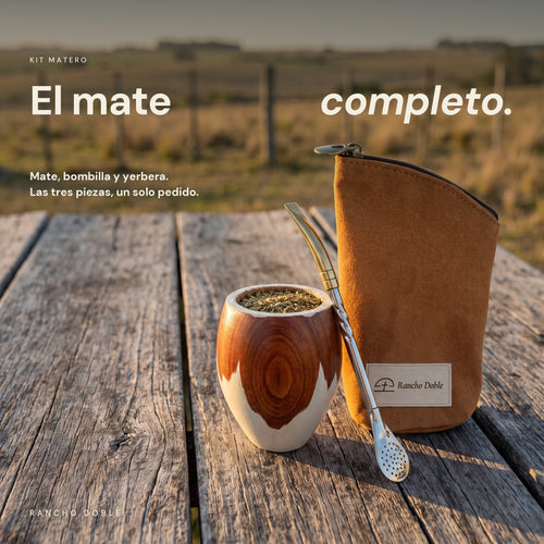 Kit matero Rancho Doble: mate de madera overo con la bombilla puesta y la yerbera de cuero de chancho camel, sobre una mesa de campo al atardecer